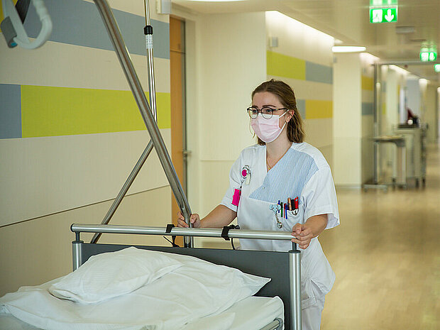 Krankenschwester schiebt Krankenbett durch den Flur 