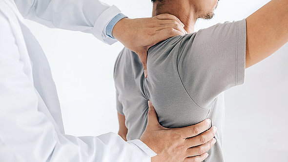 Ein Arzt untersucht die Schulter eines Patienten Ein Arzt untersucht die Schulter eines Patienten