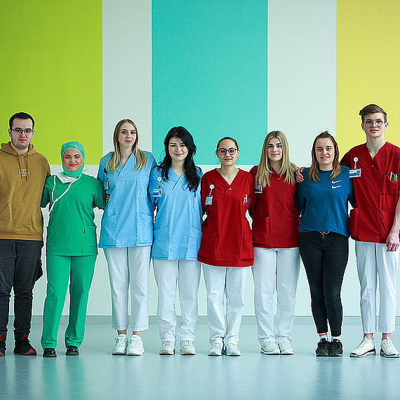 Auszubildende aller Ausbildungsberufe, die sich in den Armen halten Auszubildende aller Ausbildungsberufe, die sich in den Armen halten