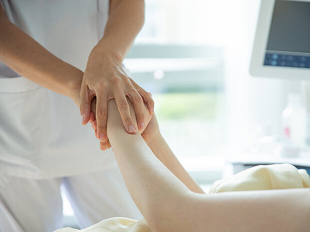Pflegekraft hält die Hände einer Patientin