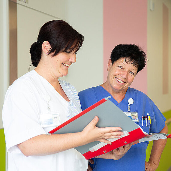 Zwei Mitarbeiterinnen auf einer Station beim Besprechen Zwei Mitarbeiterinnen auf einer Station beim Besprechen
