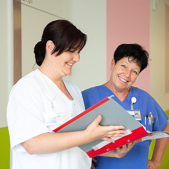 Zwei Mitarbeiterinnen auf Station mit einer Patientenakte Zwei Mitarbeiterinnen auf Station mit einer Patientenakte