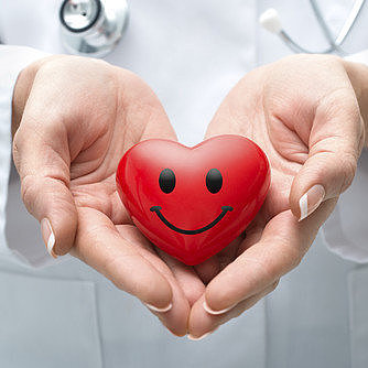 Arzt/Ärztin mit lächelndem Herz in der Hand Arzt/Ärztin mit lächelndem Herz in der Hand