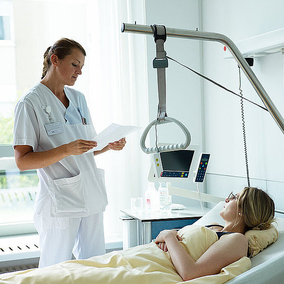 Pflegekraft am Bett einer Patientin Pflegekraft am Bett einer Patientin